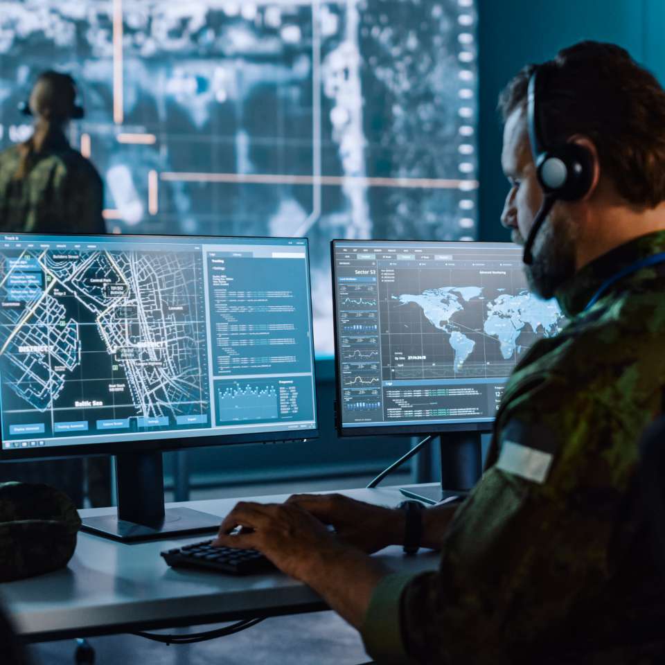 person with a headset working at a desktop in a control centre